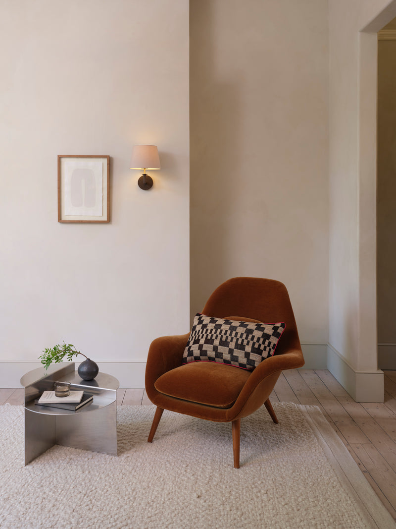 Astro Club wall light lit above a rust velvet armchair